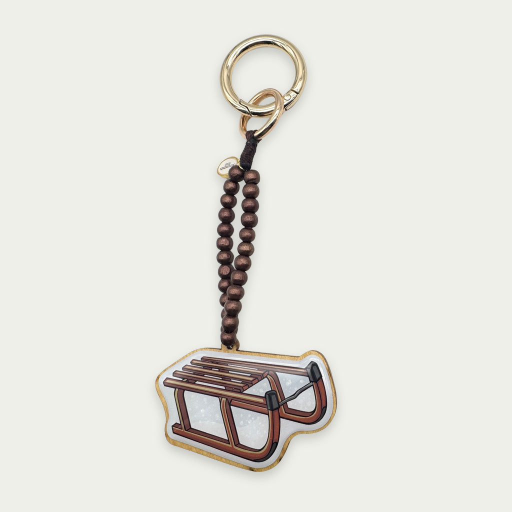 Escapulario Taschenanhänger Schlitten als verspielter winterlicher Bagcharm für Handtaschen und Taschen das perfekte Geschenk für Frauen in der Wintersaison.