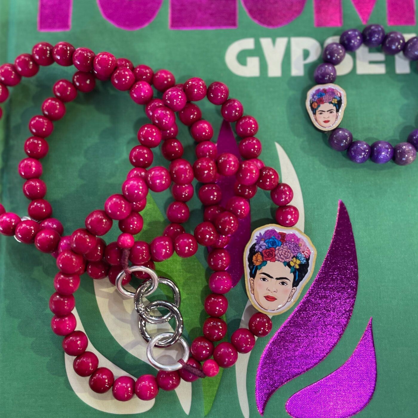 Escapulario Frida Kahlo Handykette in Pink mit Frida-Motiv, farbigen Perlen und Metallkarabinern als künstlerisches Smartphone-Accessoire für Frauen.