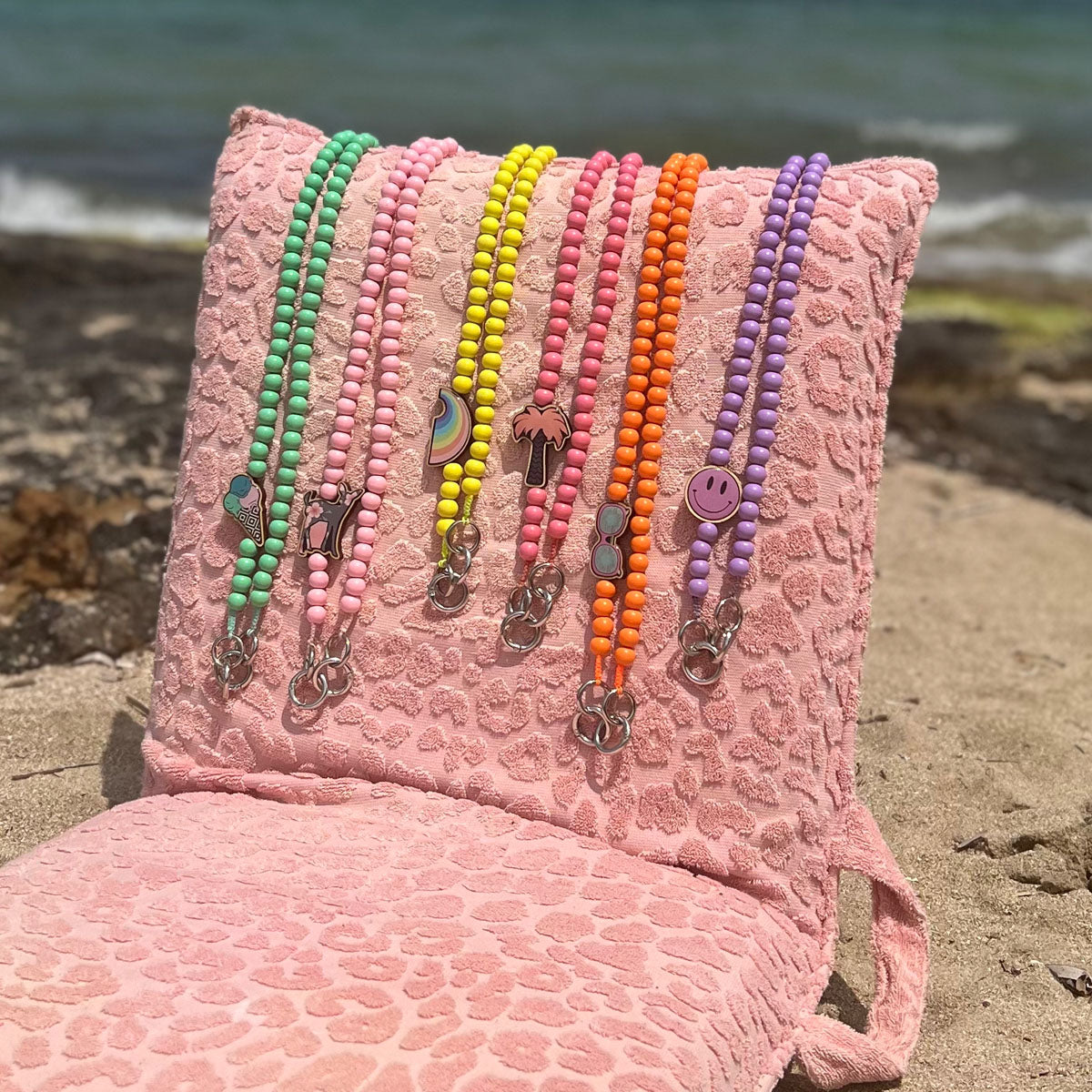 Escapulario Handykette in Neonorange mit Sonnenbrillen-Pin aus Holz und Metallkarabinern als auffälliges Smartphone-Accessoire für modebewusste Frauen.