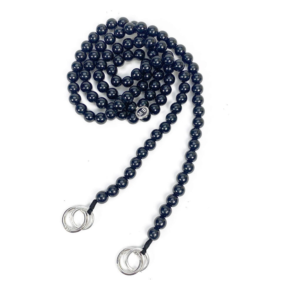 Escapulario Handykette in Schwarz mit Perlenkette und Metallkarabinern als zeitloses Smartphone-Accessoire für Frauen.