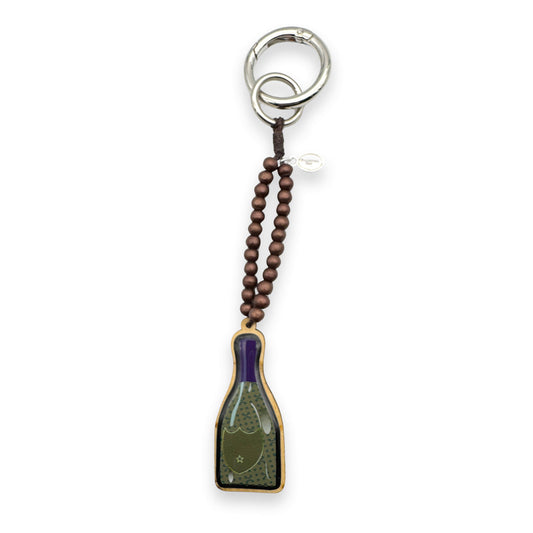Escapulario Taschenanhänger Champagnerflasche als verspielter festlicher Bagcharm für Taschen und Handtaschen als einzigartiges Accessoire für Damen.