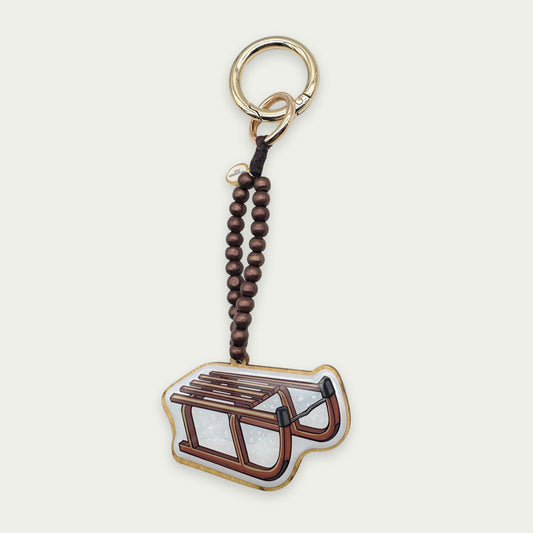 Escapulario Taschenanhänger Schlitten als verspielter winterlicher Bagcharm für Handtaschen und Taschen das perfekte Geschenk für Frauen in der Wintersaison.
